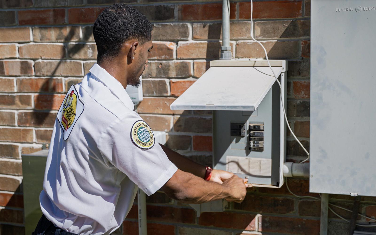 Man in Mister Sparky shirt inspects electrical panel