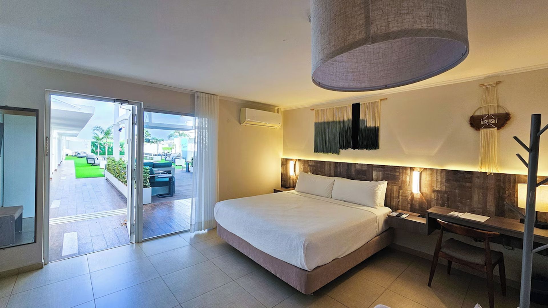 Dormitorio con cama tamaño king, escritorio y puertas corredizas de vidrio que conducen a un patio.