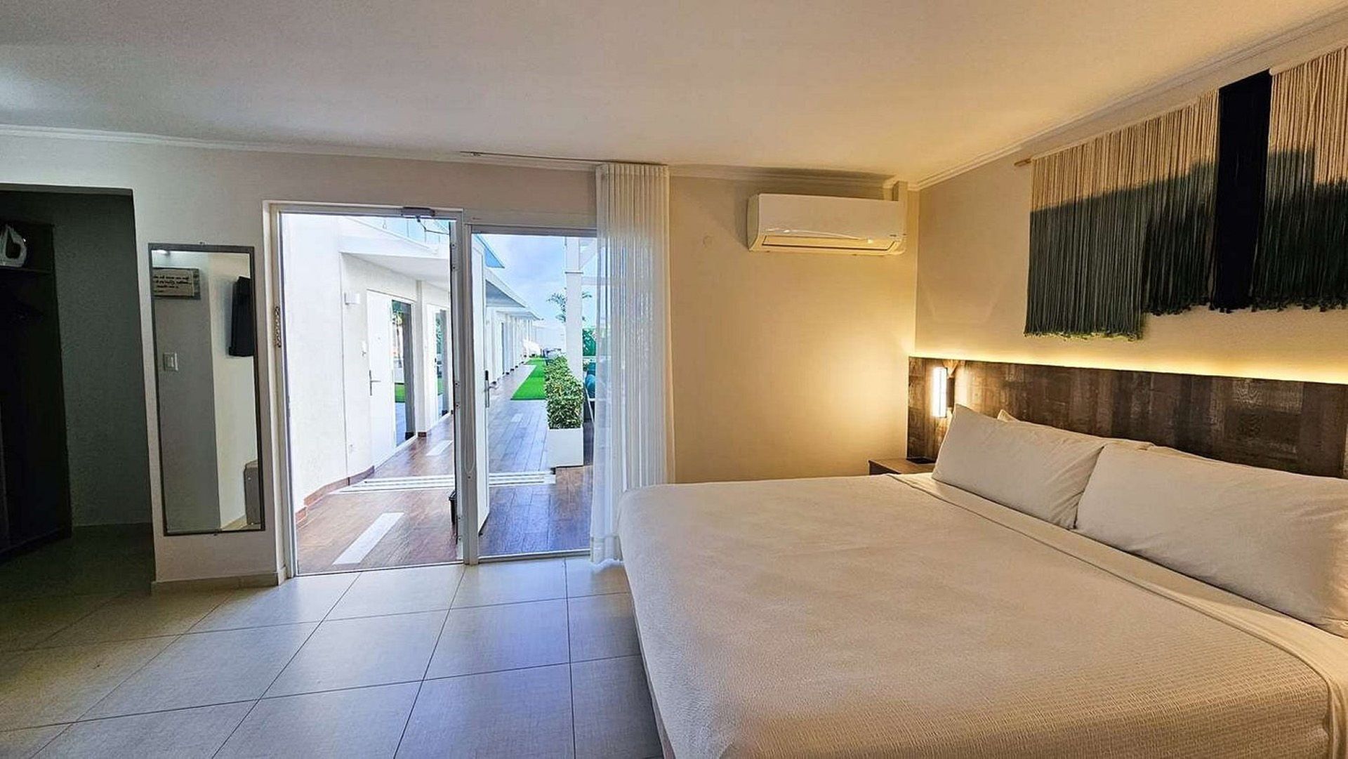 Habitación de hotel con cama King, puertas de patio abiertas y obras de arte.