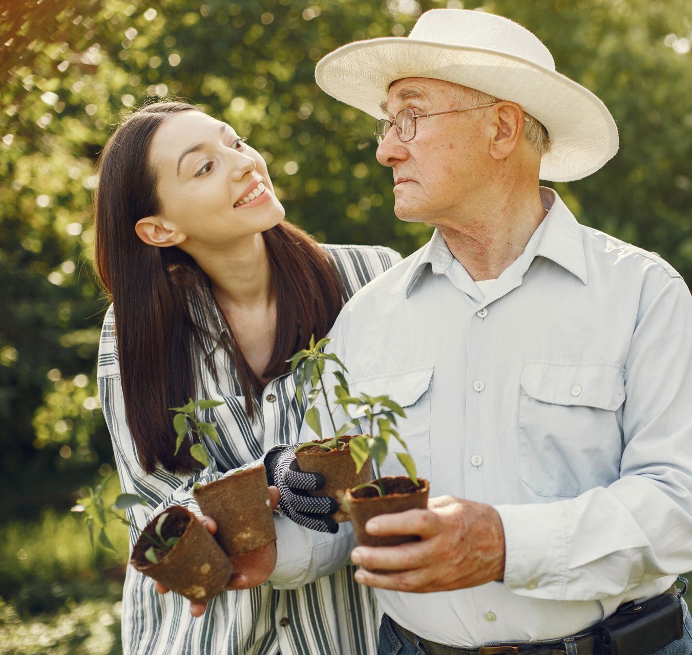 A man and a woman are holding potted plants in their hands.