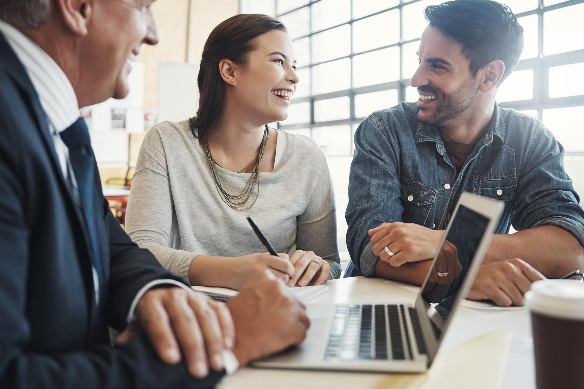 A man and a woman are sitting at a table with a laptop.