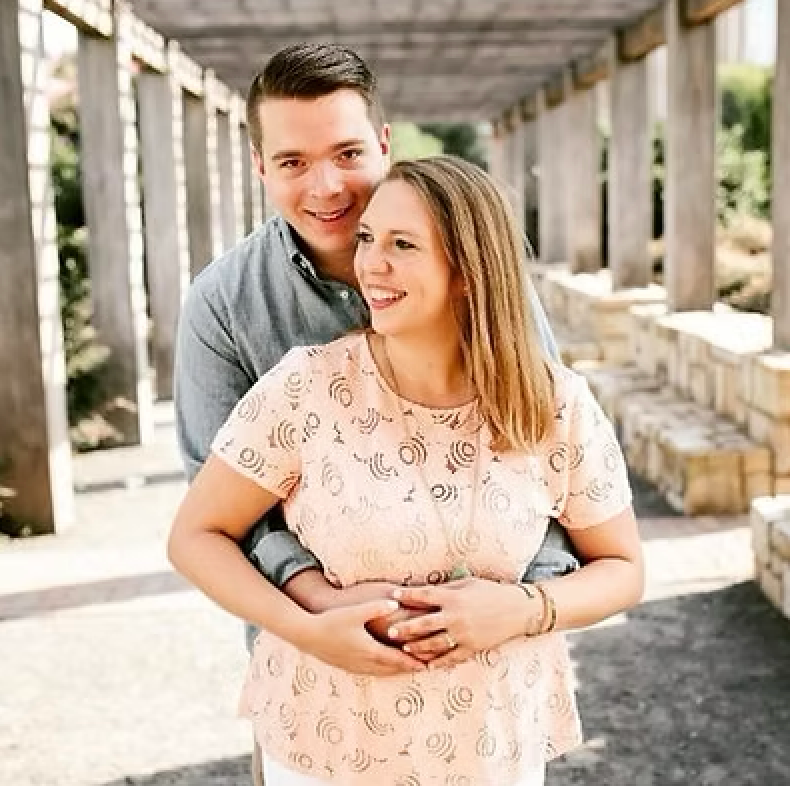 A man is hugging a woman in a pink dress.