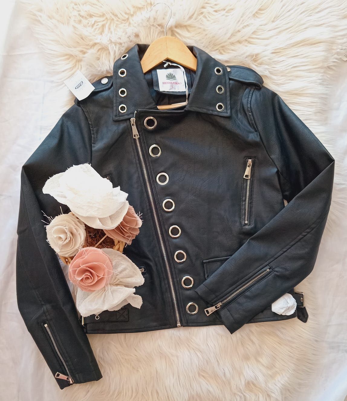 Una chaqueta de cuero negra cuelga de una percha junto a un ramo de flores.