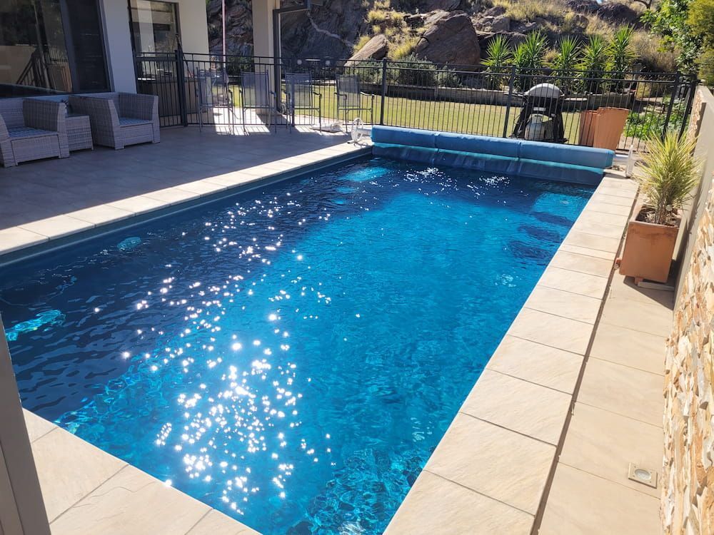 A Large Swimming Pool Is Surrounded By A Stone Wall — Burton Group In Ciccone, NT