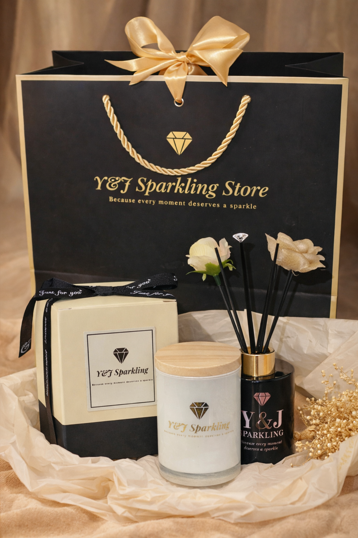 Cadeauset met producten van Y&J Sparkling Store: aromadiffuser, kaars en cadeautasje op een gouden doek.