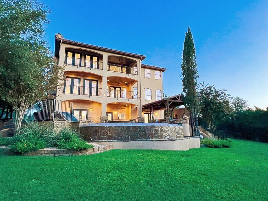 A large house with a swimming pool is sitting on top of a lush green hillside.