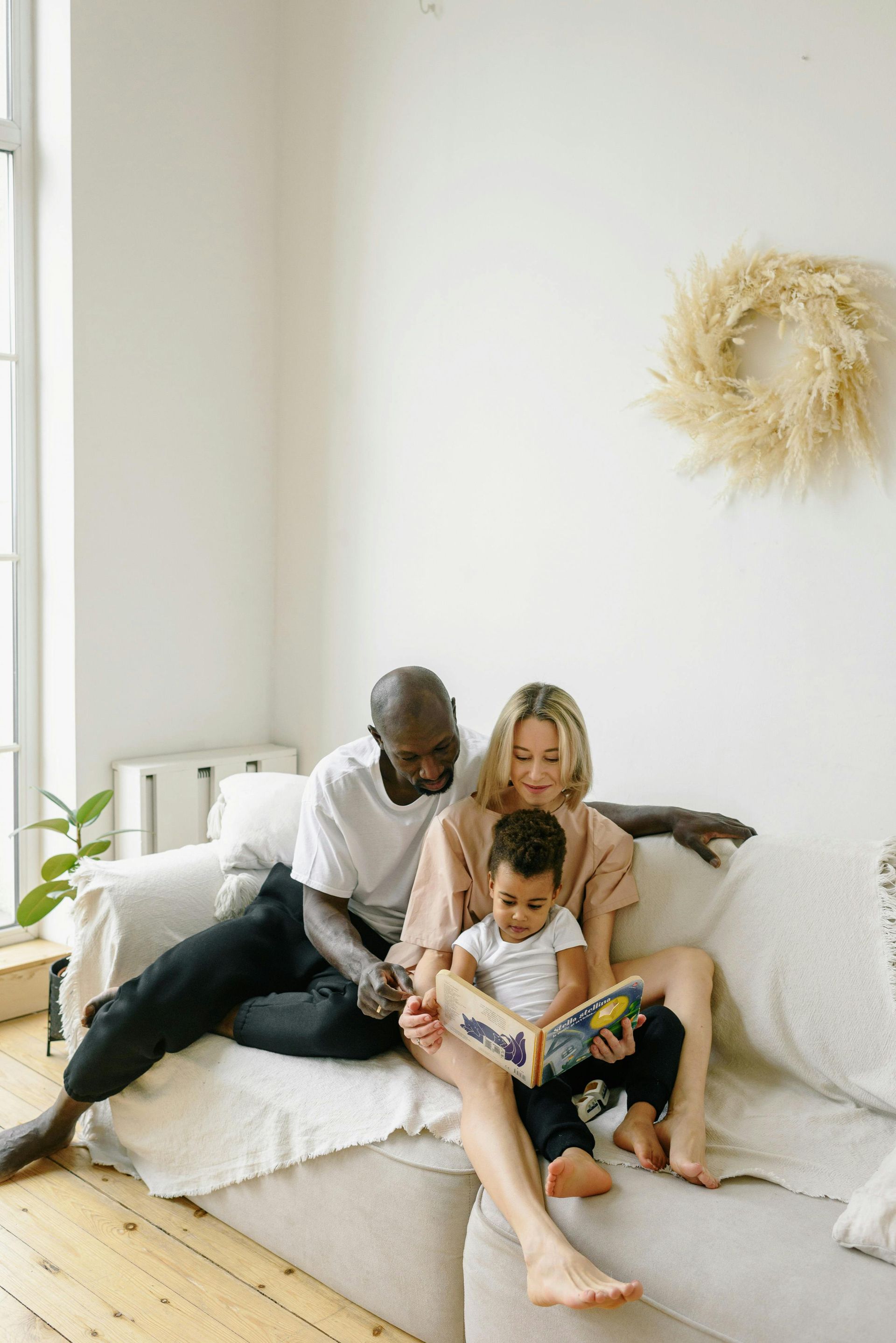 A family is sitting on a couch reading a book together.