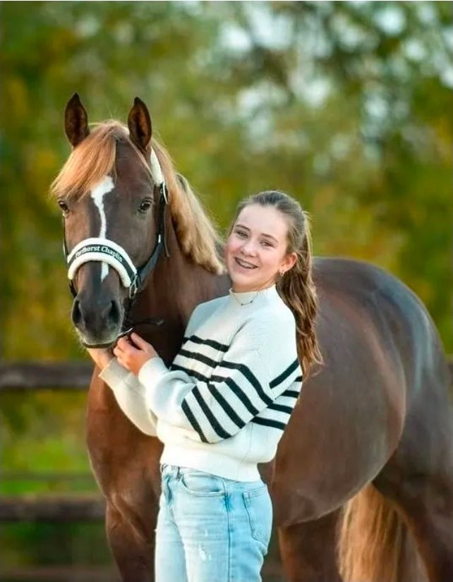 Een roze, gewatteerd tuigje met een witte voering van imitatiebont, gepersonaliseerd met de naam 