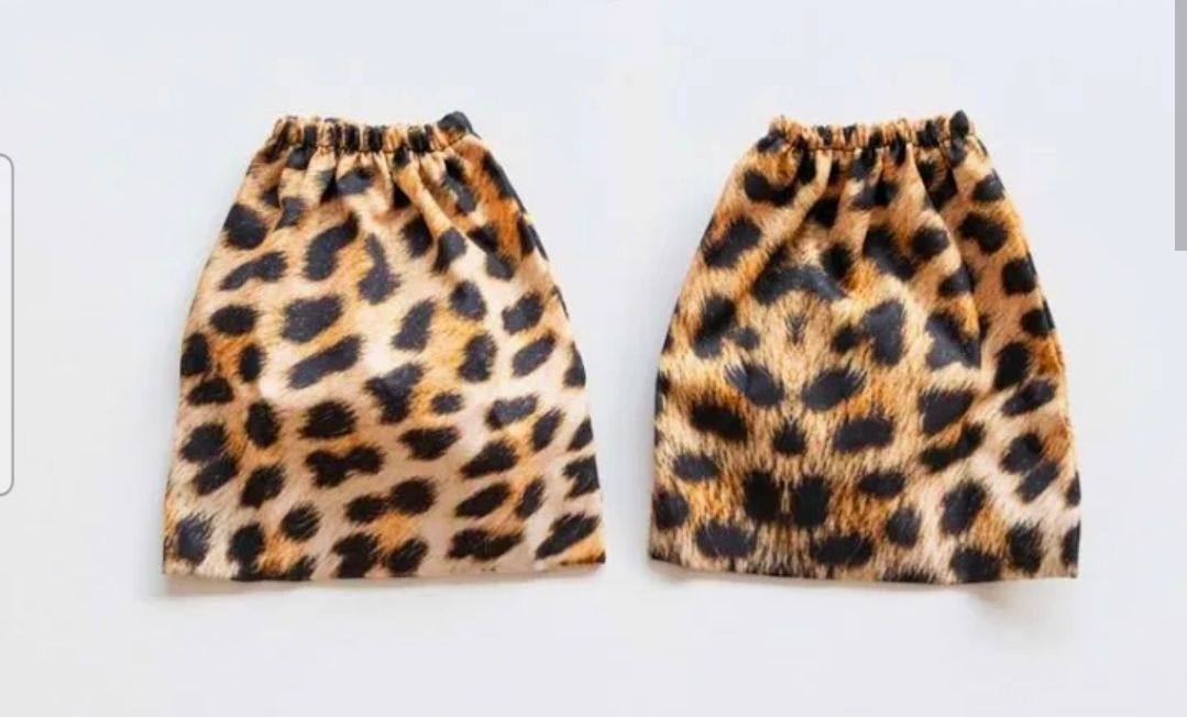 Een paar beenwarmers of laarsmanchetten van luipaardprintstof met elastische boorden, afgebeeld op een witte achtergrond.