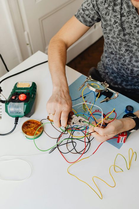 Electrical Service Precision LLC - A person is sitting at a table working on a project with wires.