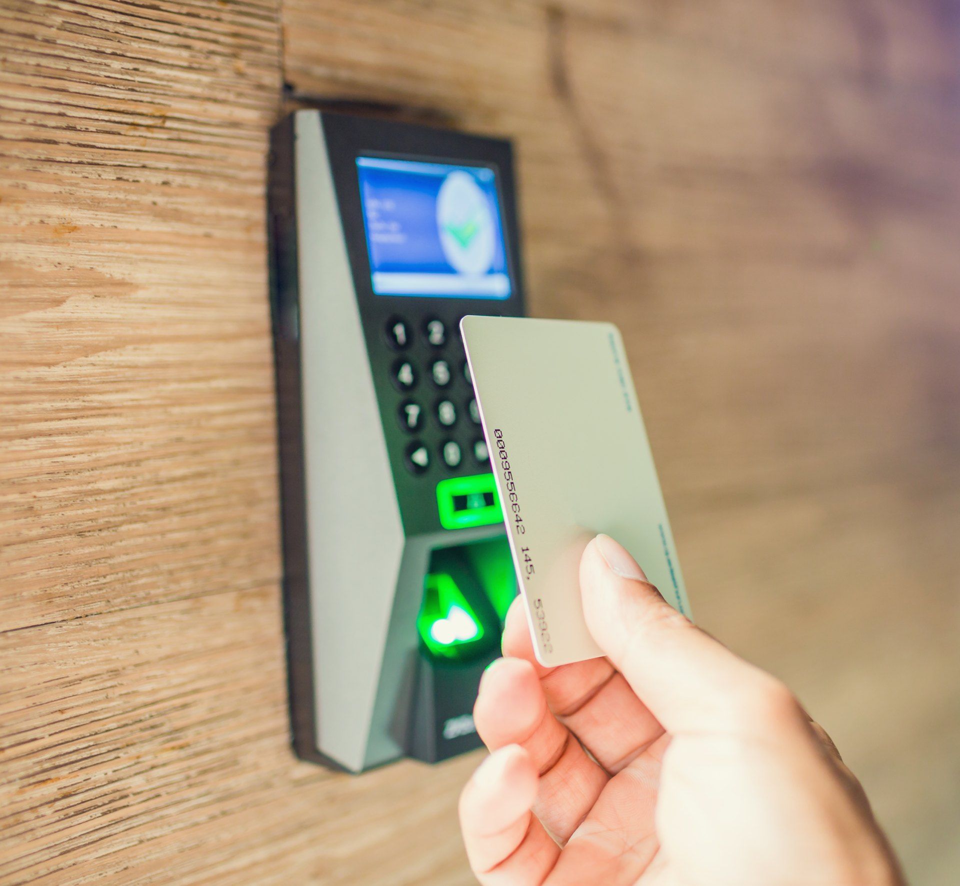 A person is holding a card in front of a fingerprint scanner.
