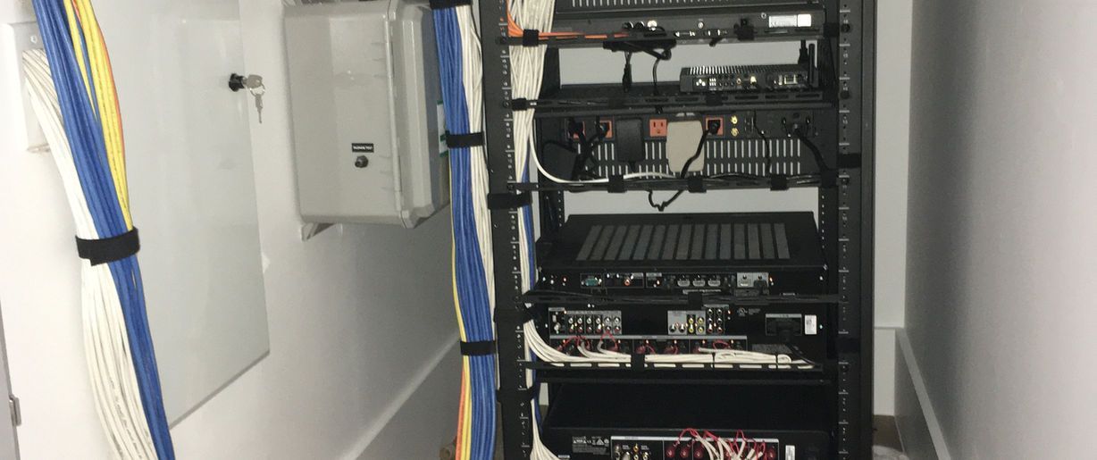 A server rack with a lot of wires hanging from it in a room.