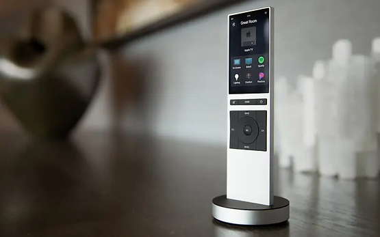 A remote control is sitting on a wooden table.