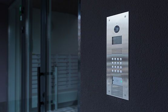 A doorbell is hanging on a wall next to a glass door.
