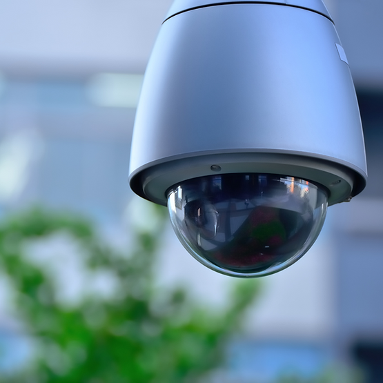 A security camera is hanging from the ceiling with a blurry background
