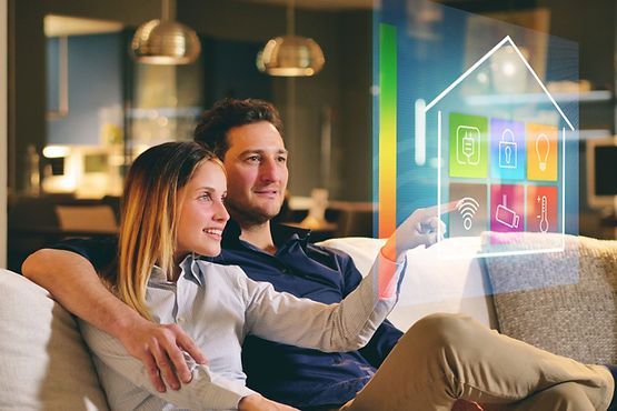 A man and a woman are sitting on a couch looking at a smart home.