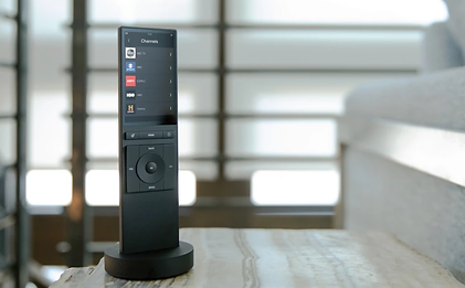 A black remote control is sitting on a wooden table.
