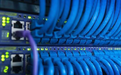 A bunch of blue cables are connected to a server in a data center.