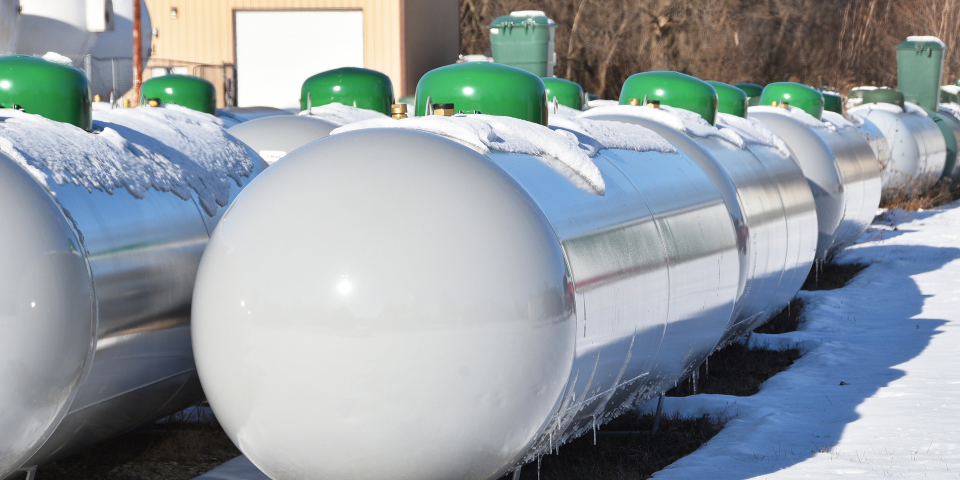 A row of propane tanks are lined up in the snow.