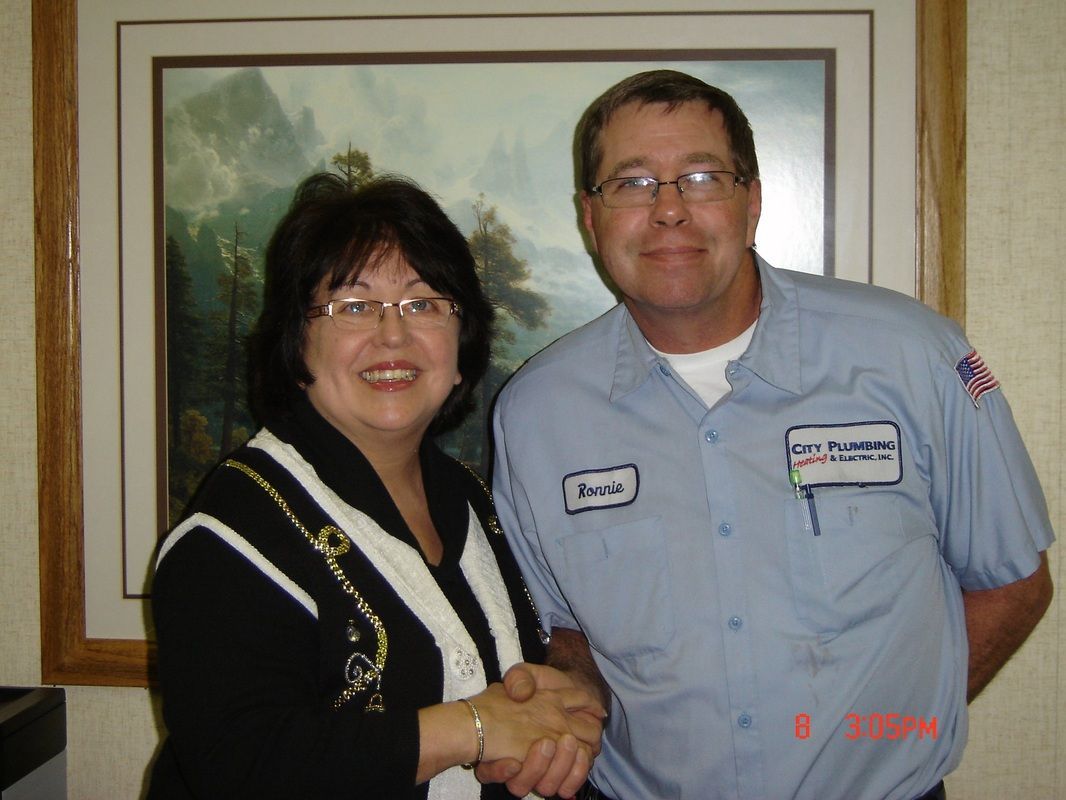 A man and a woman are shaking hands in front of a painting