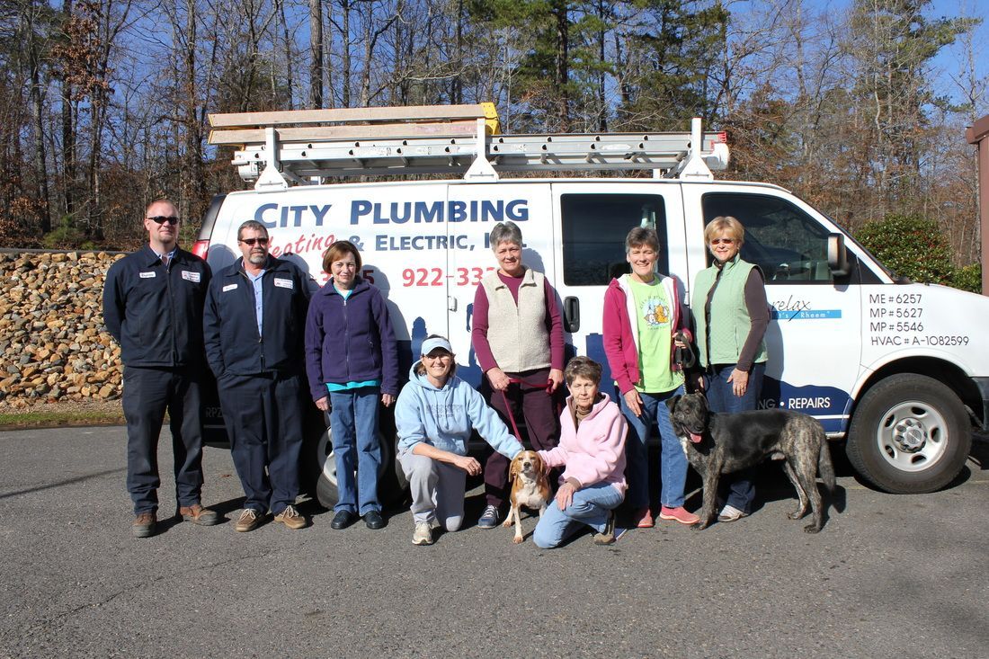 A group of people standing in front of a city plumbing van