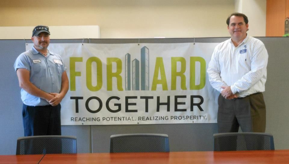 Two men standing in front of a sign that says forward together