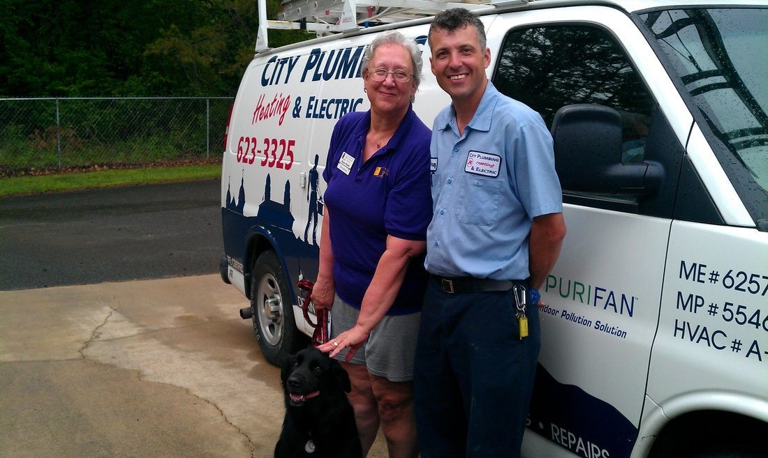 A man and woman standing in front of a city plumbing van