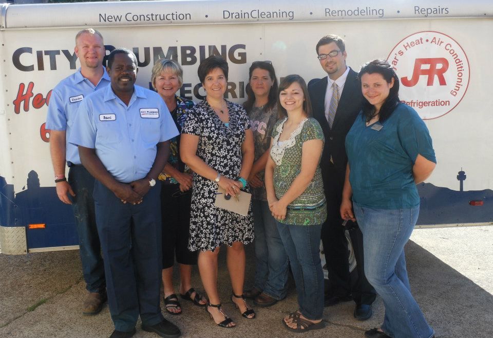 A group of people standing in front of a city plumbing truck