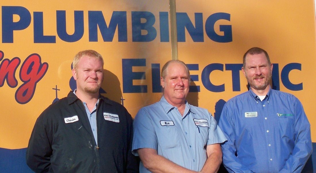 Three men standing in front of a plumbing electric sign