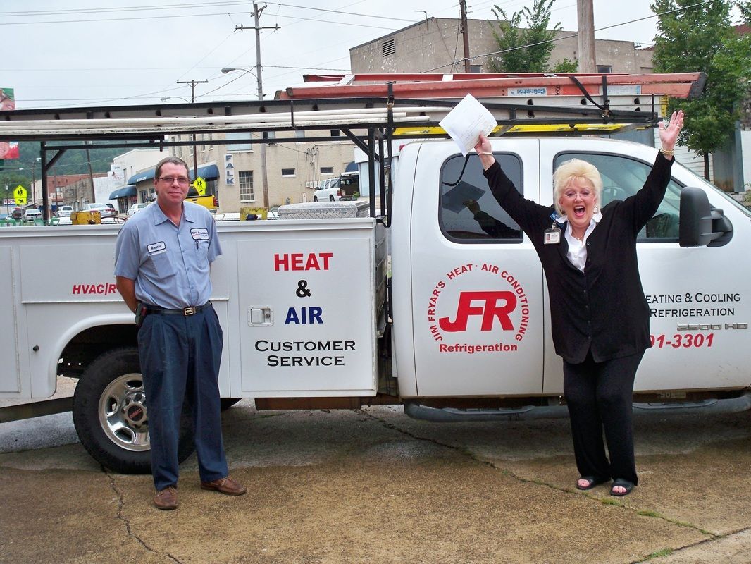 A man and a woman standing in front of a heat and air truck