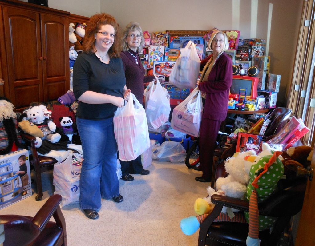 Three women are standing in a room full of stuffed animals