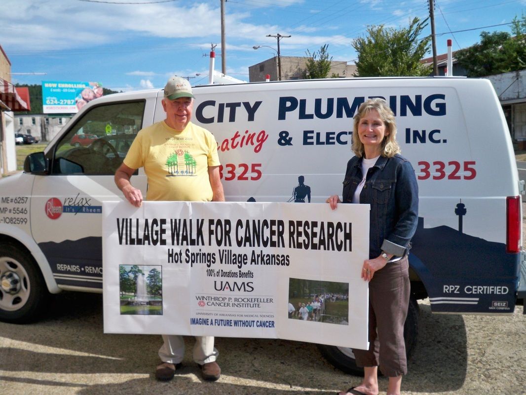 Two people holding a sign in front of a city plumbing van