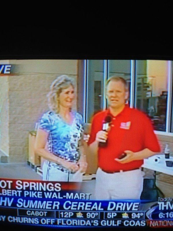 A man in a red shirt is holding a microphone and talking to a woman