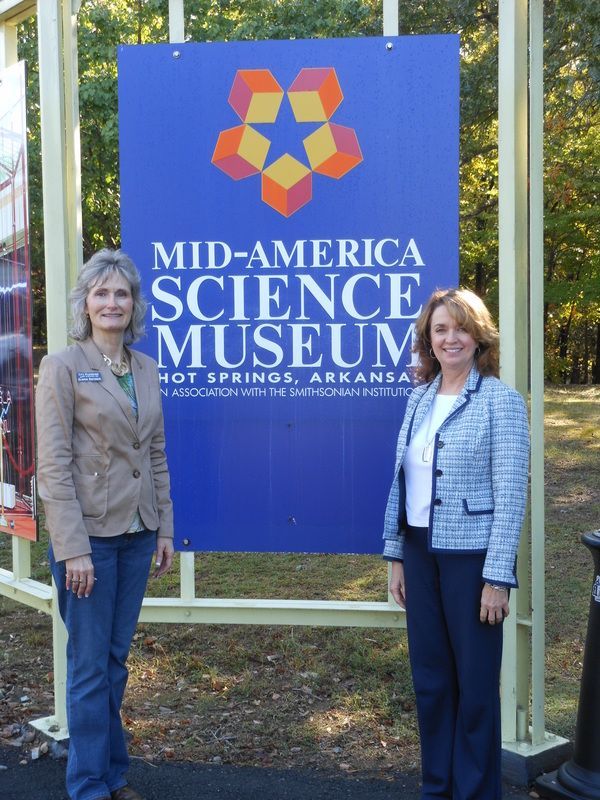 Two women stand in front of a sign for the mid-america science museum