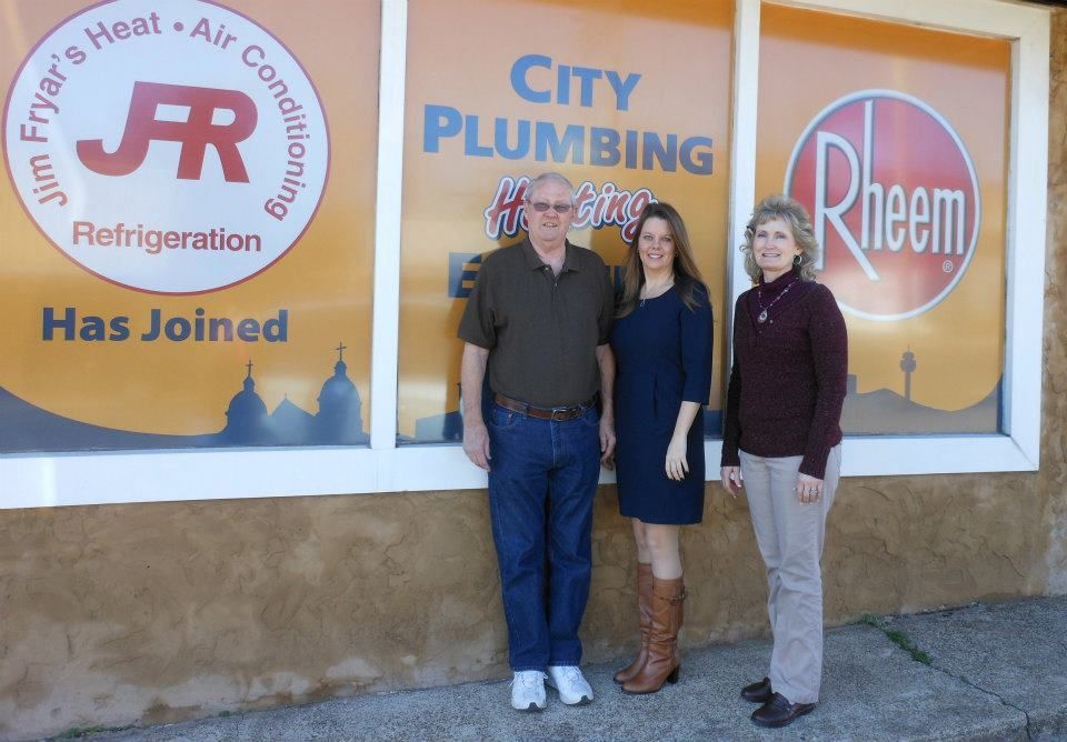 Three people standing in front of a window that says city plumbing