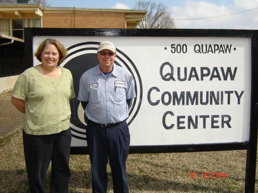 A man and woman stand in front of a quapaw community center sign