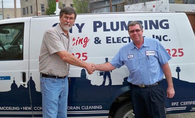 Two men shaking hands in front of a plumbing van