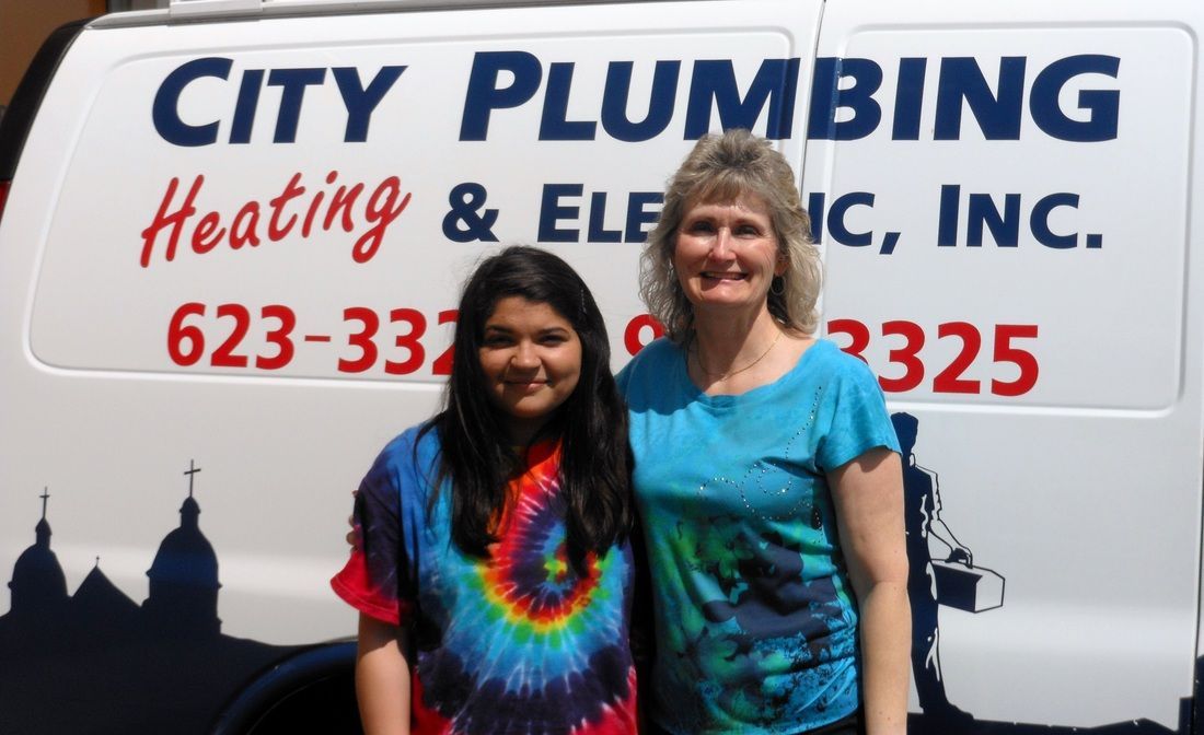 Two women standing in front of a city plumbing van