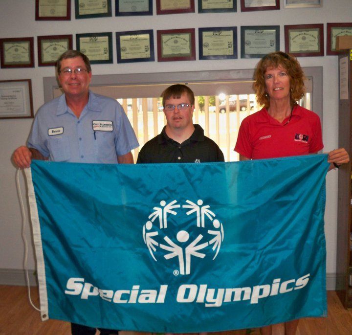 Three people holding a special olympics flag