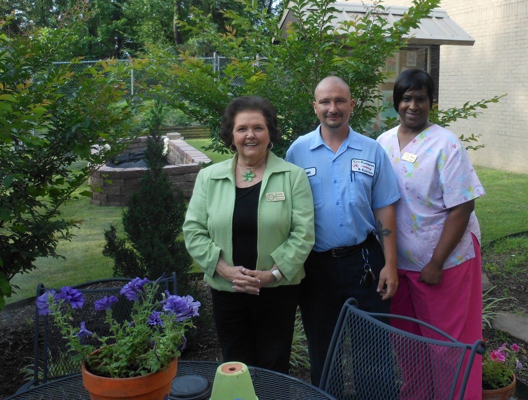 A man and two women are posing for a picture in a garden