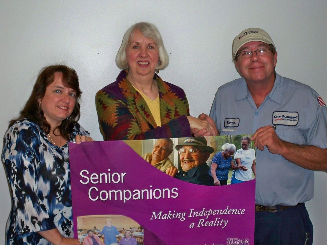 Three people holding a sign that says senior companions