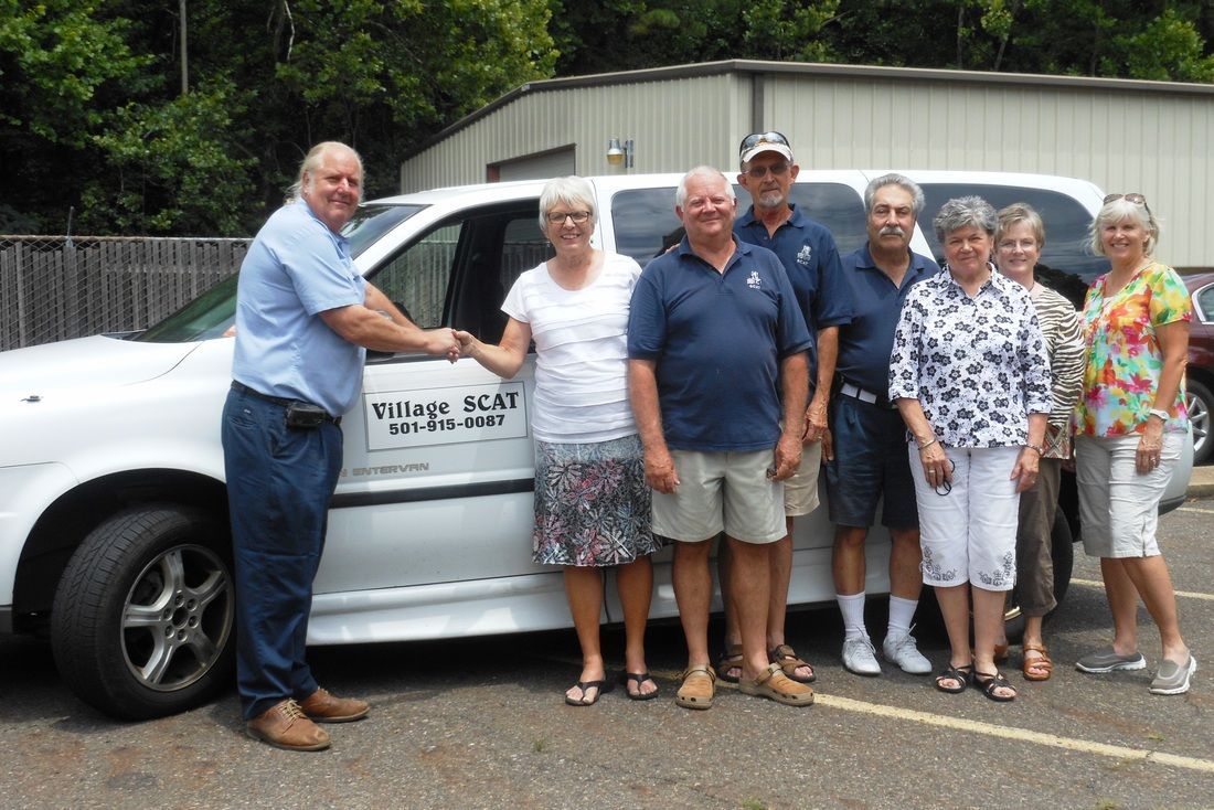 A group of people are standing in front of a white van.