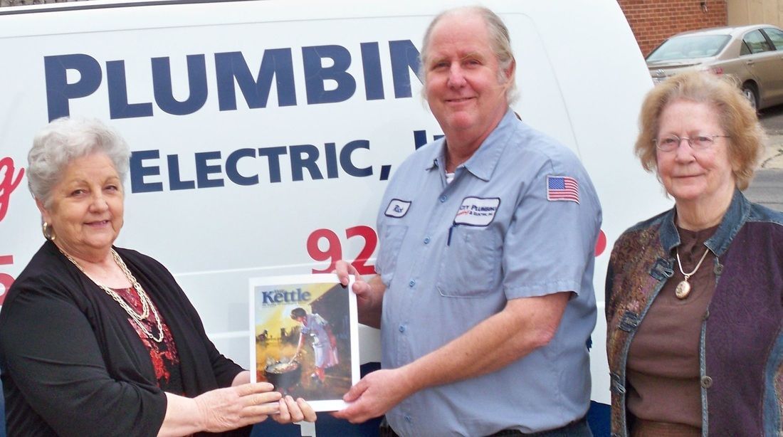 A man and two women standing in front of a plumbing van