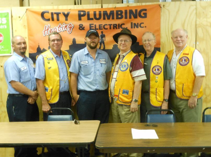 A group of men standing in front of a sign that says city plumbing & electric inc.