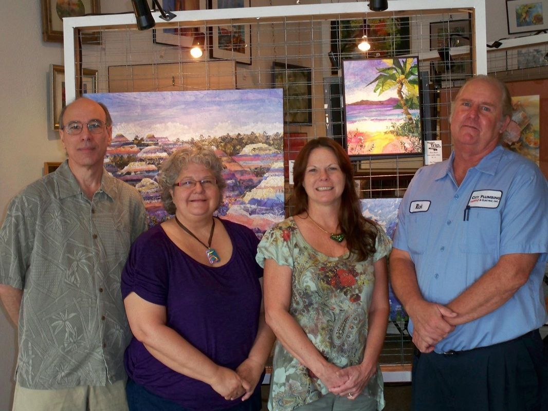 A group of people posing for a picture in front of paintings