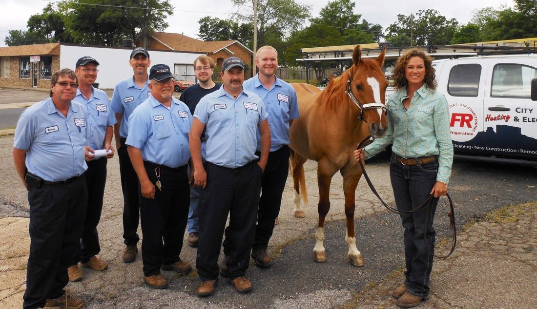 A group of people standing next to a brown horse