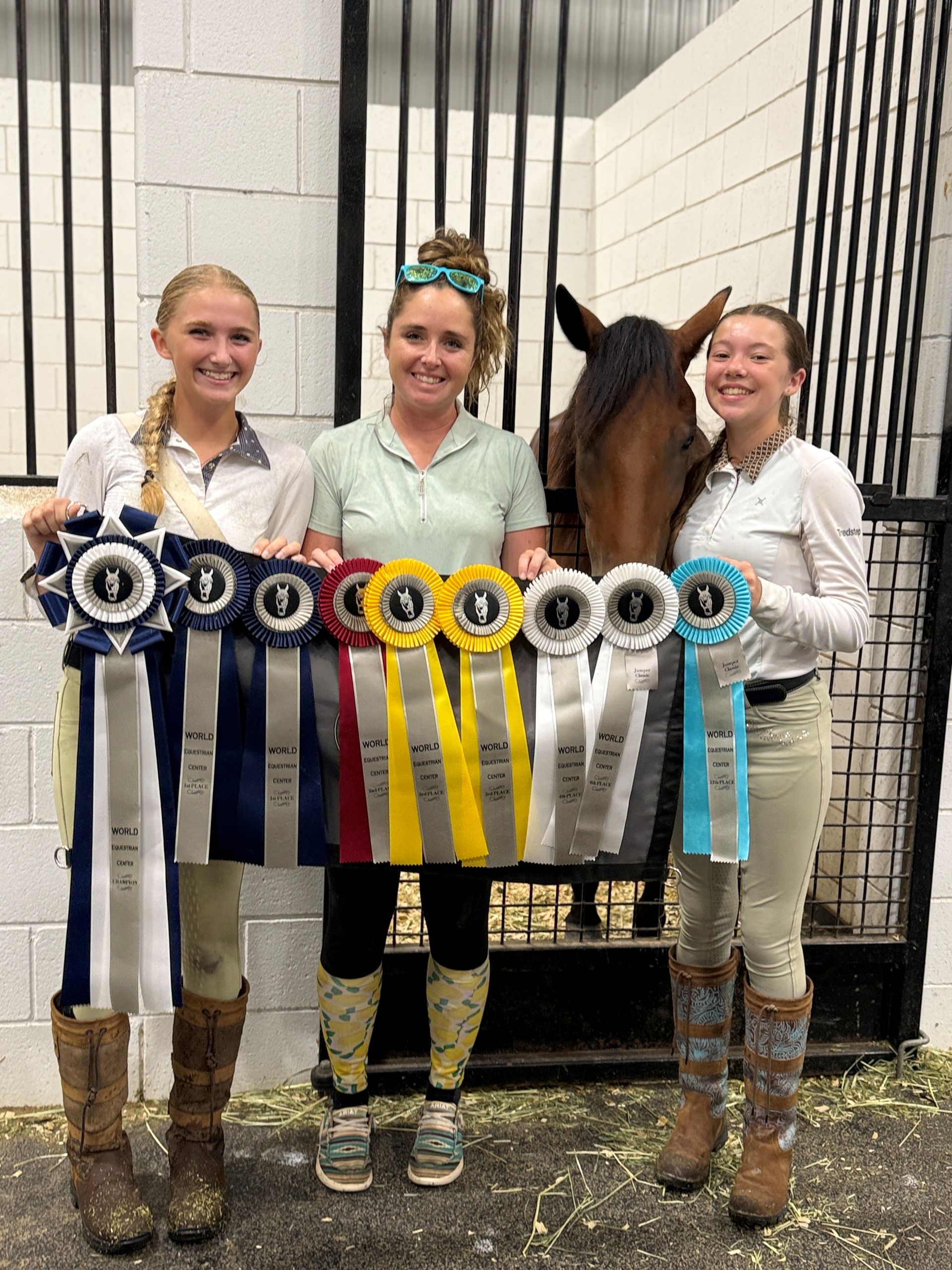 Three people and a horse with ribbons, in stable.