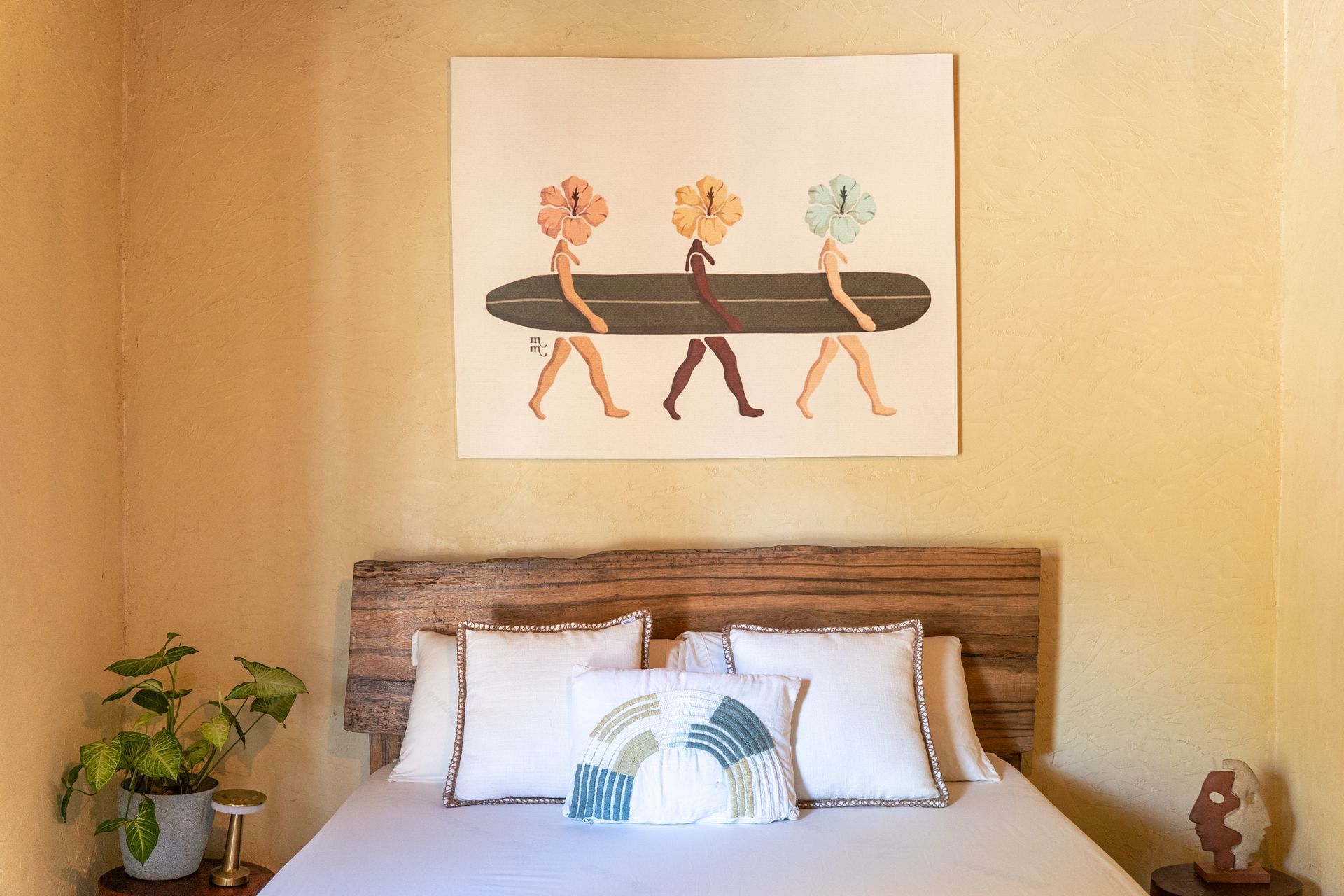 Cozy bedroom with wooden bed, floral artwork, potted plant, and warm beige walls
