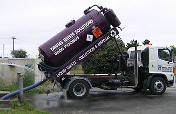 A vacuum truck is parked on the side of the road.