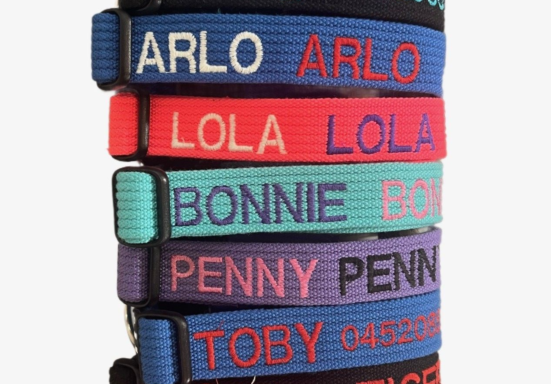 Pile of dog collars in various colors, each embroidered with a dog's name and phone number — Pet ID Collars in Wamberal, NSW